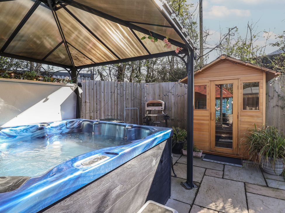 A garden with a hot tub and a wooden shed at Applejacks Orchard in Holywell