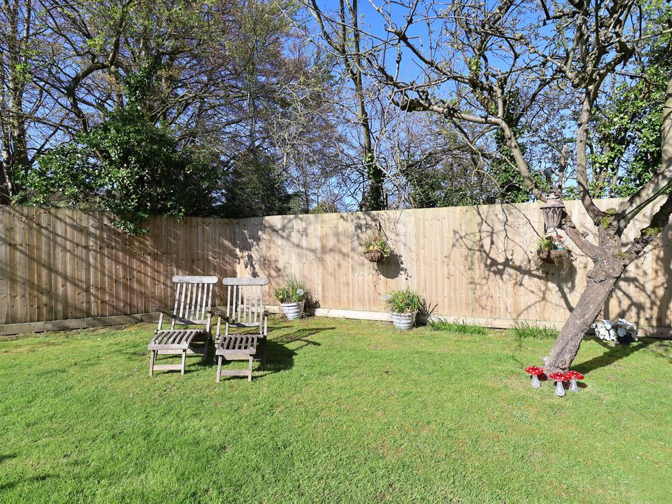 A garden with deck chairs and trees at Applejacks Orchard in Holywell