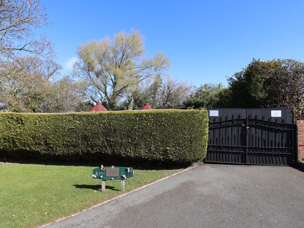 An entrance gate with a sign and a hedge at Applejacks Orchard in Holywell
