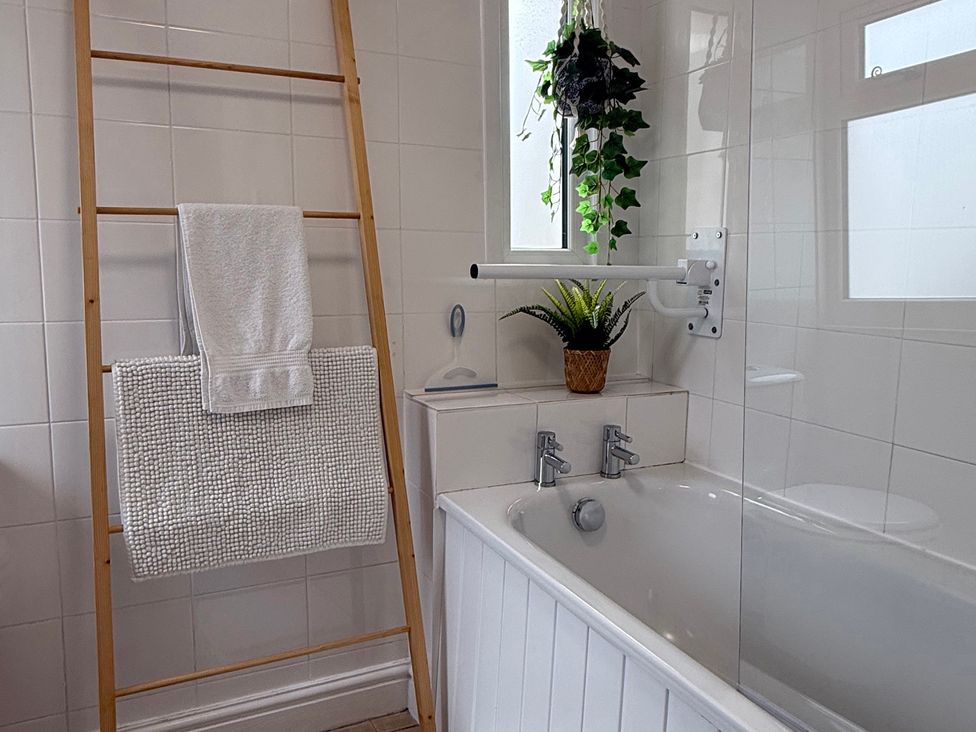 A bathroom with tub and towel rack at Waves End in Mevagissey