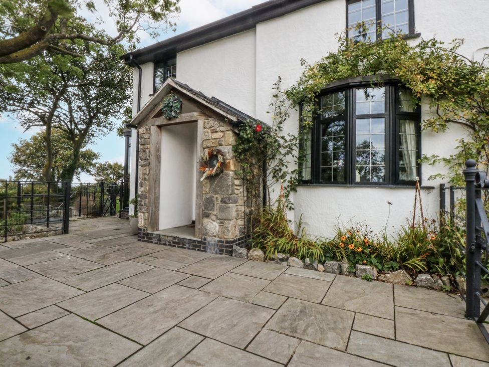 An outdoor entrance with stone pathway and flower arrangement at Windyridge in Gwaenysgor, near Prestatyn
