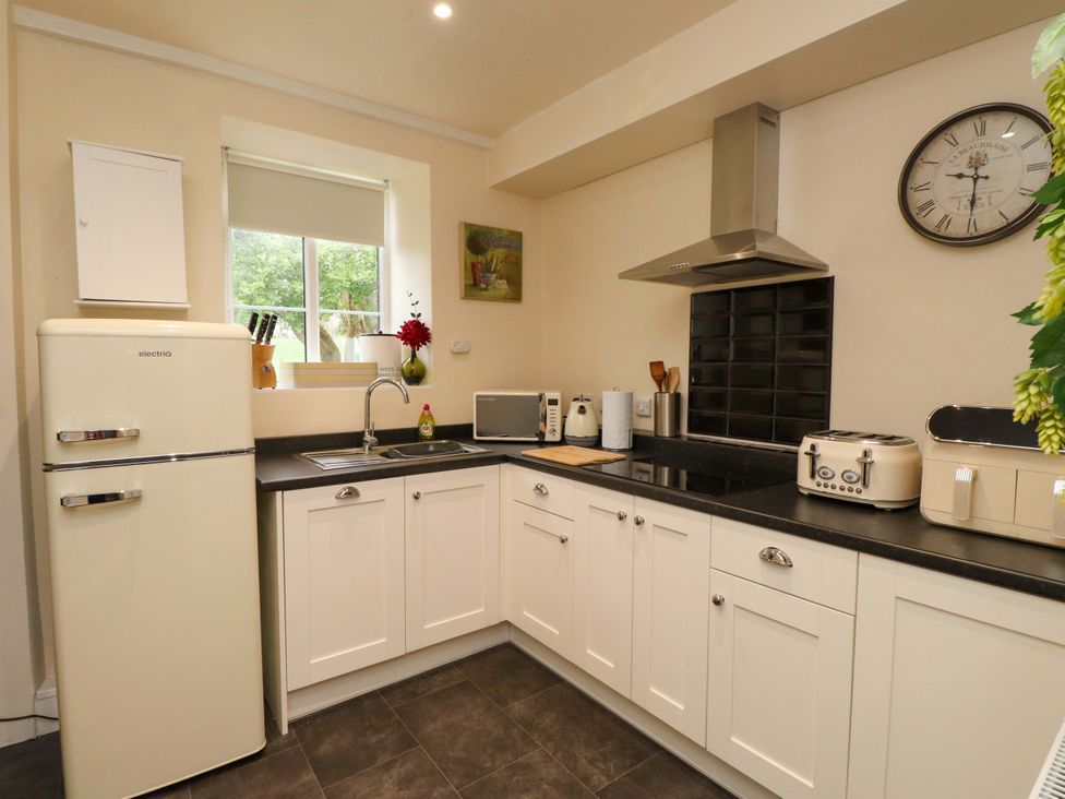 A kitchen with appliances and cabinets at Mallards Rest in Llandwrog near Bontnewydd, Gwynedd