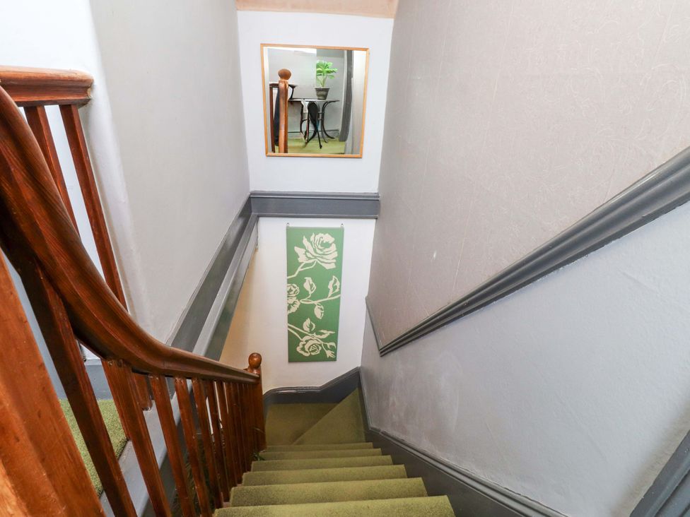 A staircase with a wooden handrail leading to a landing at Mallards Rest in Llandwrog near Bontnewydd, Gwynedd