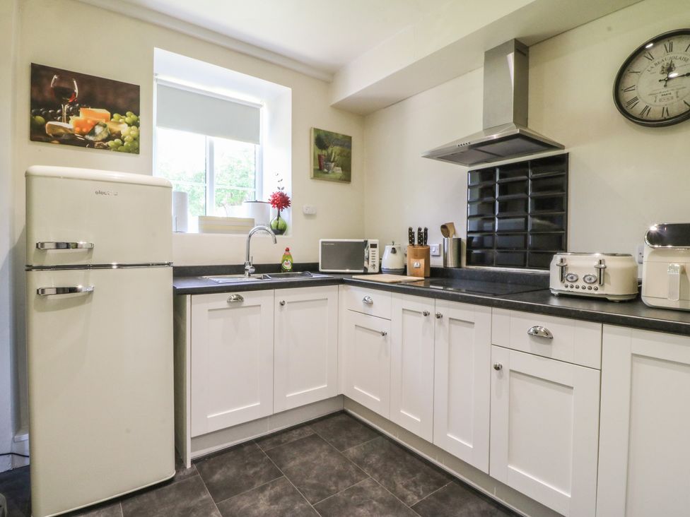 A kitchen with a refrigerator, sink, microwave, and cabinets at Mallards Rest in Llandwrog near Bontnewydd, Gwynedd