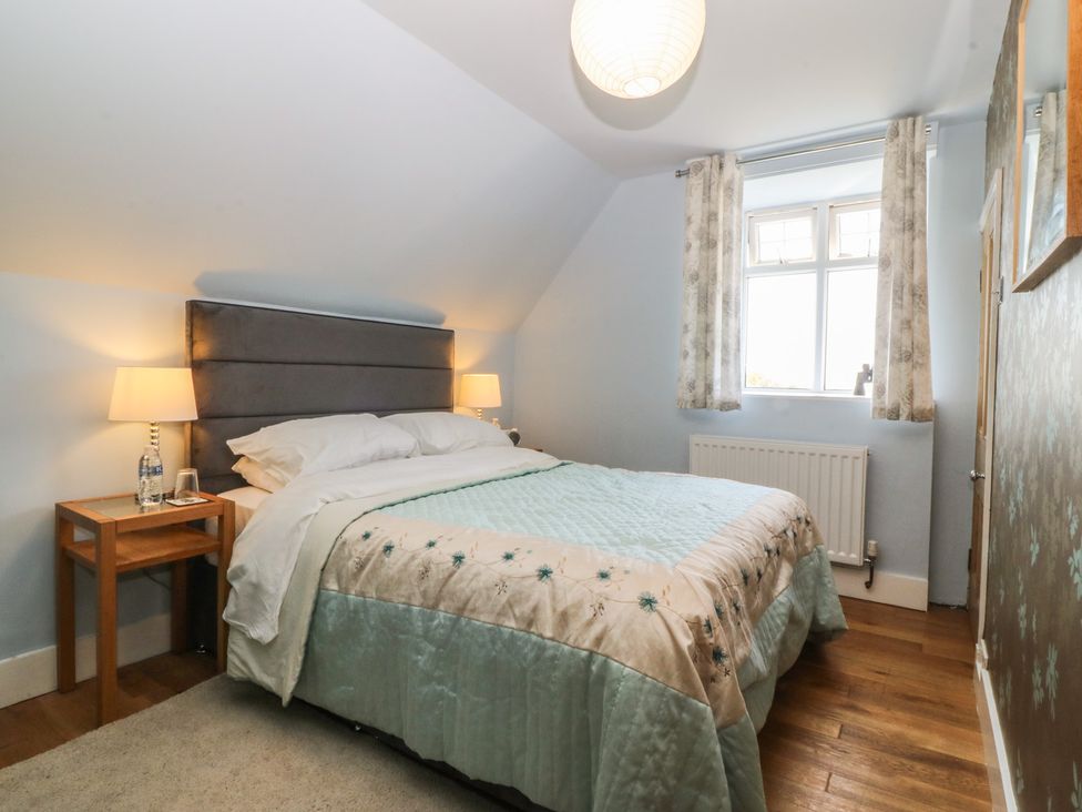 A bedroom with a bed, bedside table, and window at Mallards Rest, Llandwrog near Bontnewydd, Gwynedd