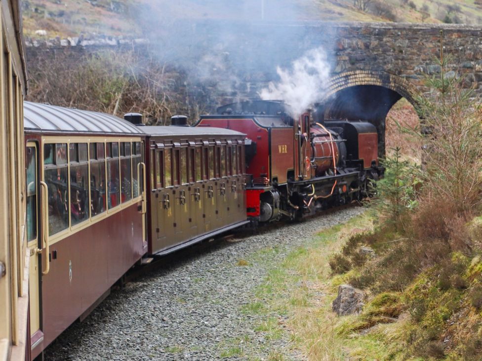 A steam train passing under a bridge in rural scenery at Mallards Rest Llandwrog near Bontnewydd, Gwynedd