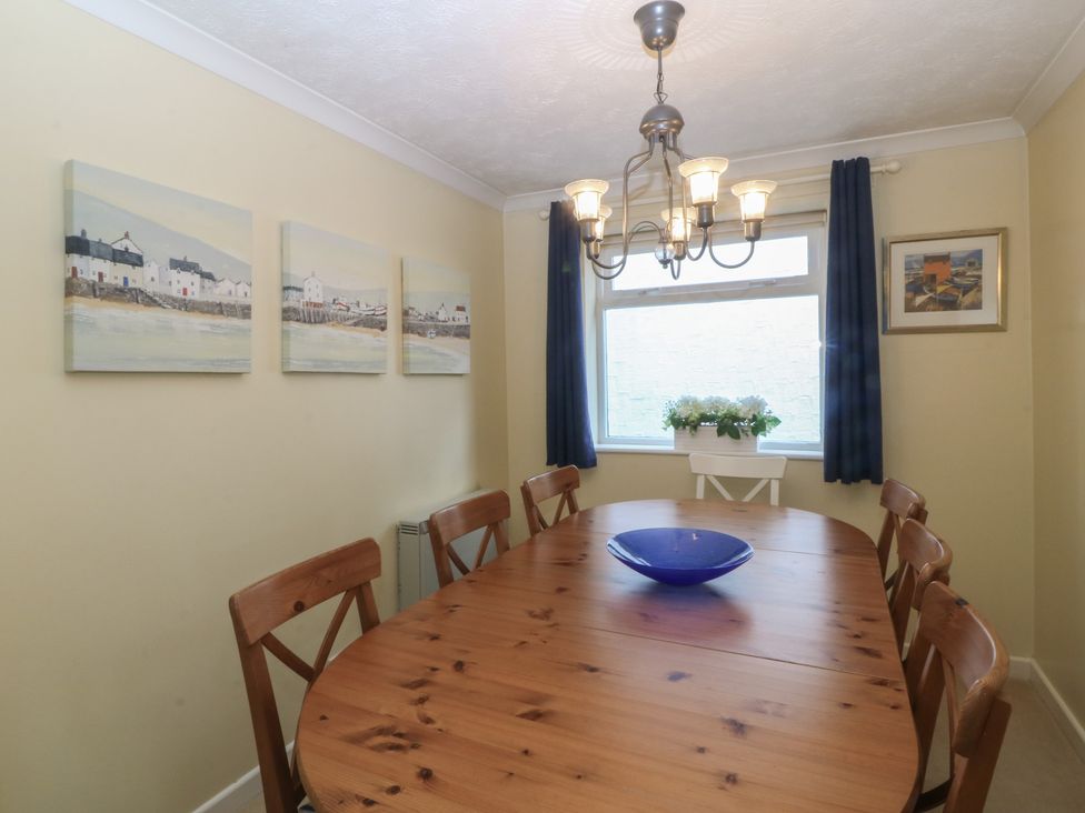 A dining room with a wooden table and paintings at Wingelock in Rhosneigr