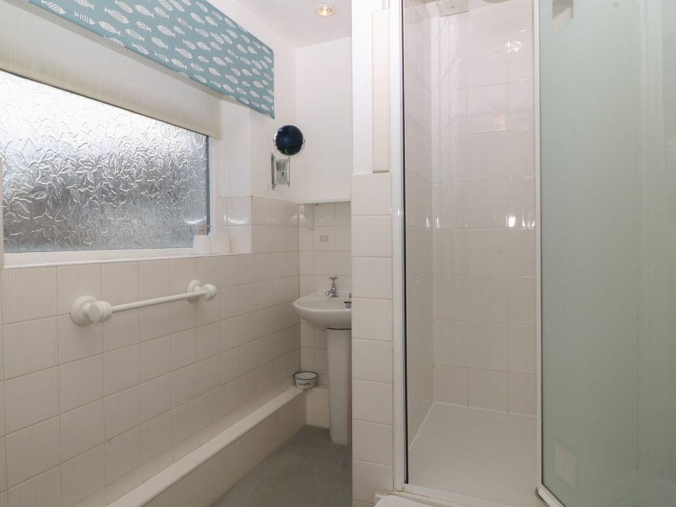A bathroom featuring a shower, sink and towel rail at Wingelock in Rhosneigr