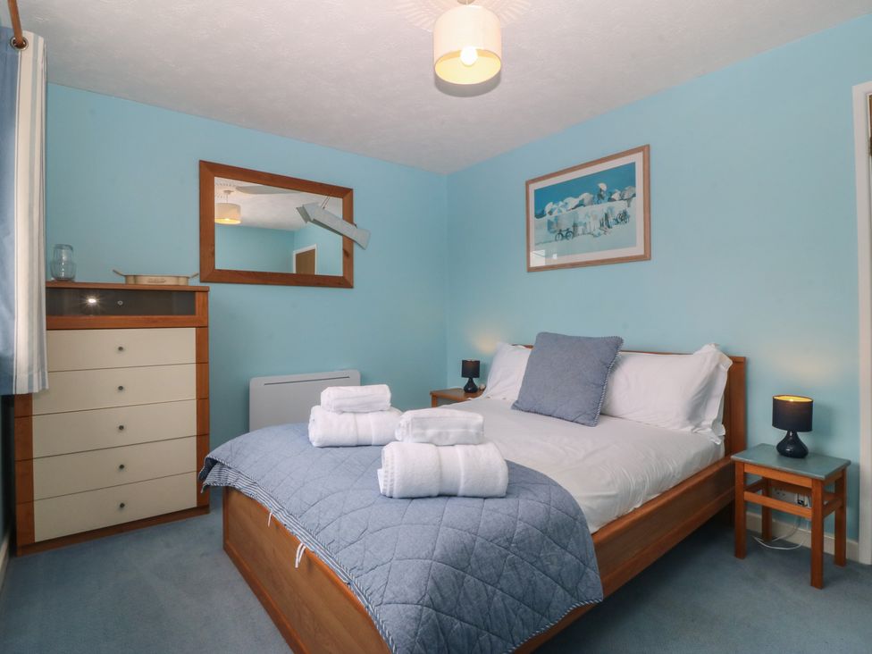 A bedroom with a bed and dresser at Wingelock Rhosneigr