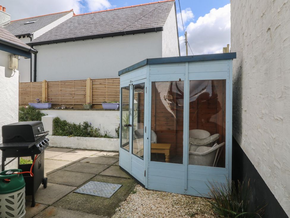 A garden with a glass porch and barbecue at Wingelock in Rhosneigr