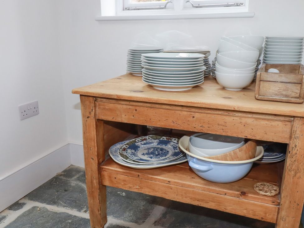 A wooden table with stacked plates and bowls in a kitchen at 84 Fore Street