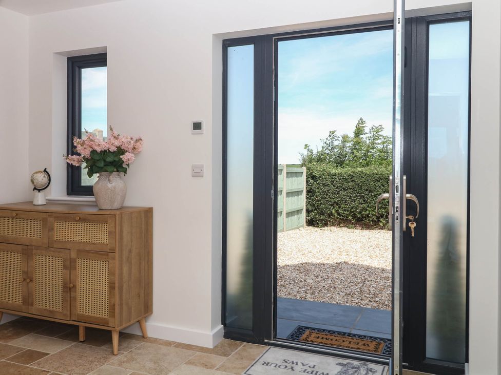 An entrance with a console table and flowers at Harescombe Lodge Morchard Bishop