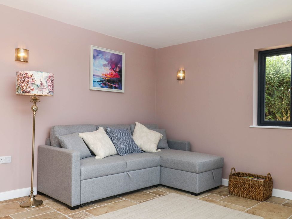 A living room with a grey sofa and a painting at Harescombe Lodge Morchard Bishop