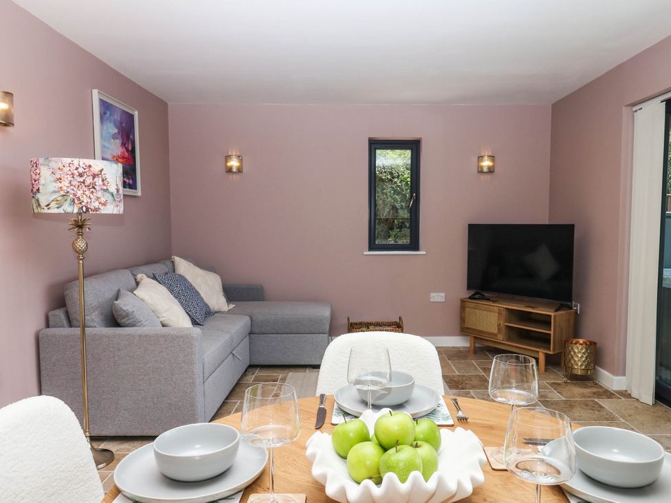 A dining room with a table and sofa at Harescombe Lodge in Morchard Bishop