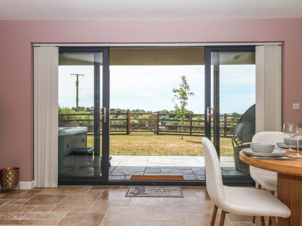 A dining room with sliding doors leading to a garden at Harescombe Lodge Morchard Bishop