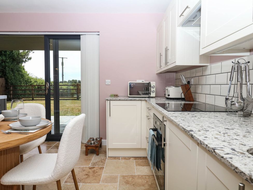 A kitchen with appliances and a dining table at Harescombe Lodge in Morchard Bishop