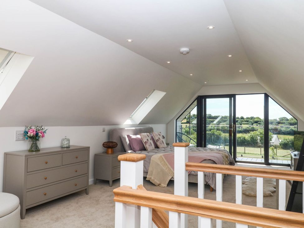 A bedroom with a bed and balcony at Harescombe Lodge in Morchard Bishop