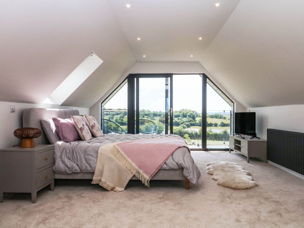 A bedroom with a bed and television at Harescombe Lodge in Morchard Bishop