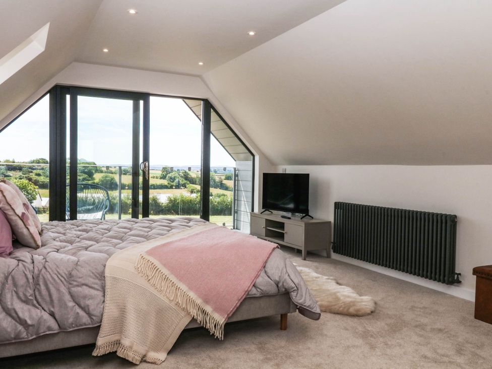A bedroom with a bed and television at Harescombe Lodge in Morchard Bishop