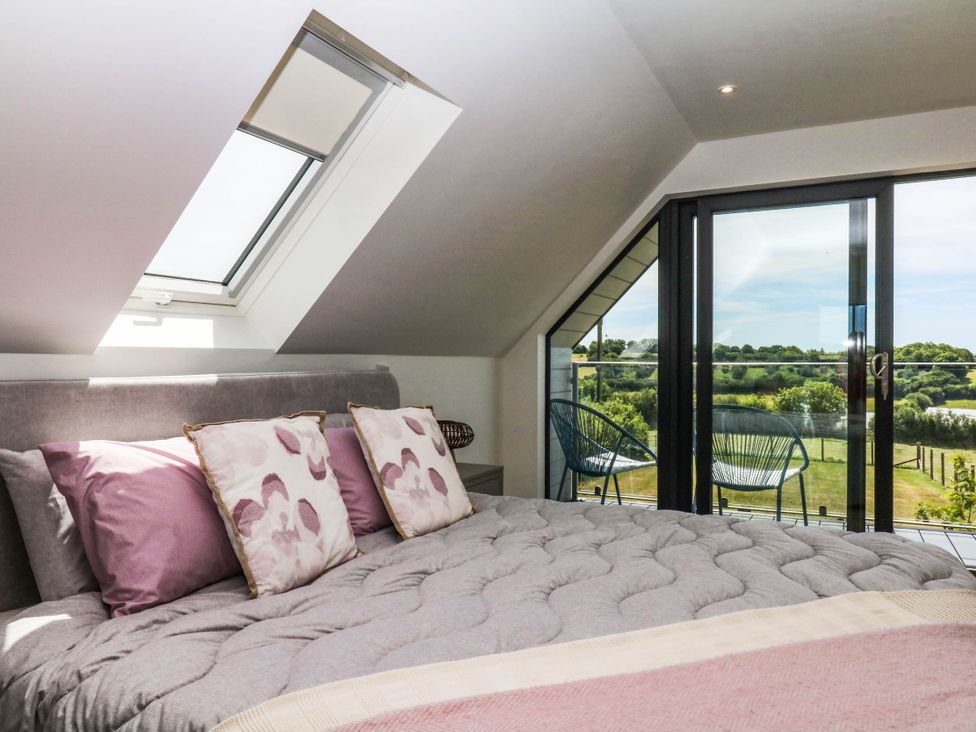 A bedroom with a bed near a balcony at Harescombe Lodge in Morchard Bishop