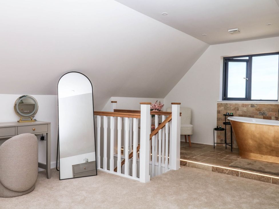 A bathroom with a bathtub and a mirror at Harescombe Lodge in Morchard Bishop