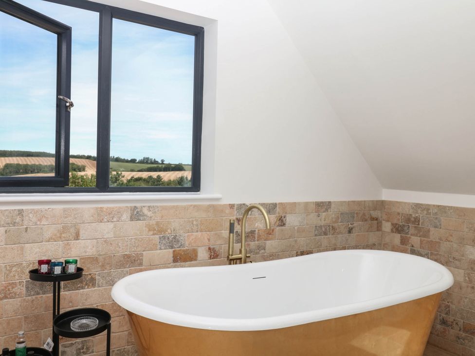 A bathroom with a bathtub near a window at Harescombe Lodge Morchard Bishop