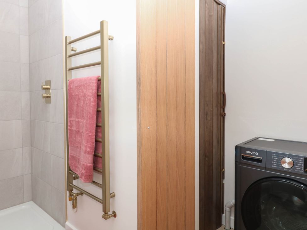 A bathroom featuring a shower, towel rail, and washing machine at Harescombe Lodge in Morchard Bishop