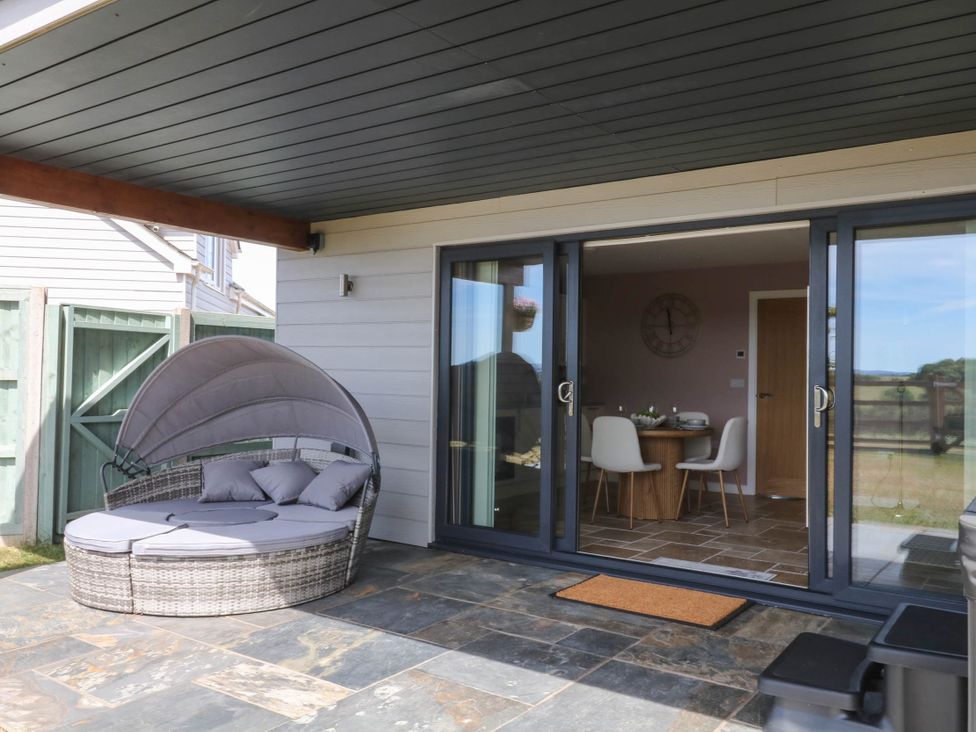 An outdoor area with a patio and sliding glass doors at Harescombe Lodge in Morchard Bishop