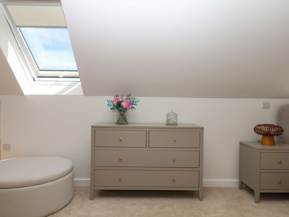 A bedroom with a dresser and flowers at Harescombe Lodge in Morchard Bishop