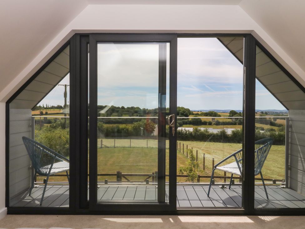 A balcony with chairs and a landscape view at Harescombe Lodge in Morchard Bishop