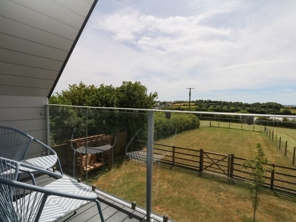 A balcony with a chair overlooking a garden at Harescombe Lodge in Morchard Bishop