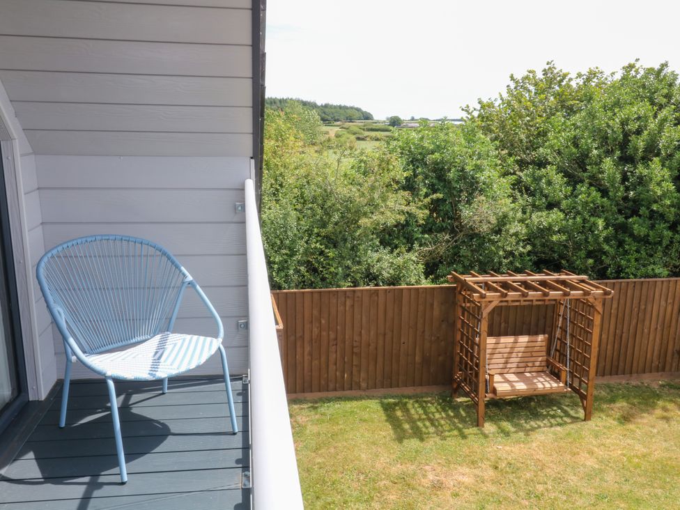 A balcony with a chair and swing at Harescombe Lodge in Morchard Bishop
