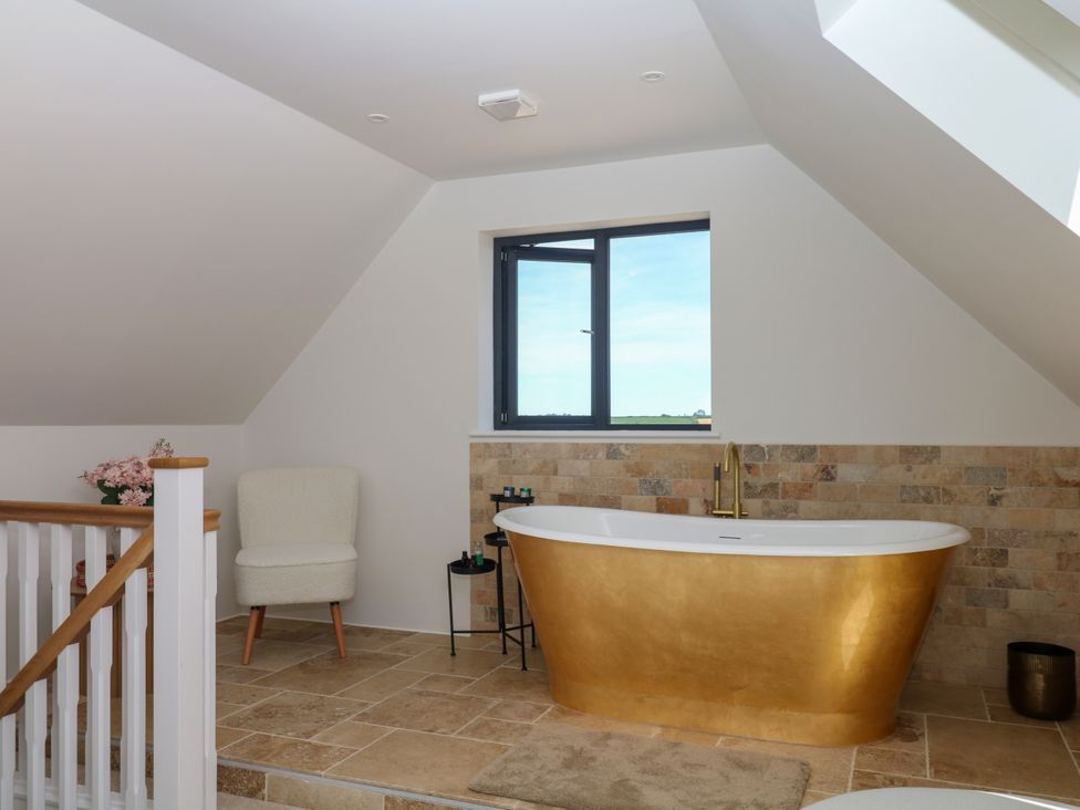 A bathroom with a bathtub and a chair at Harescombe Lodge in Morchard Bishop