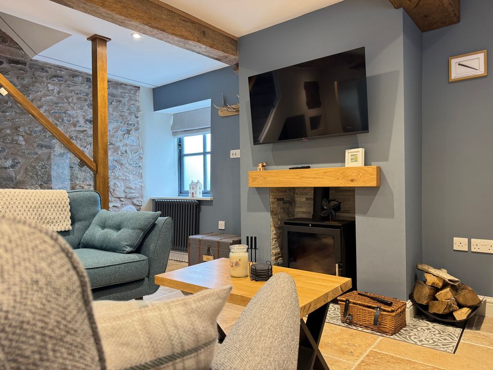 A living room with a television and a fireplace at Railway Cottage in Penybontfawr