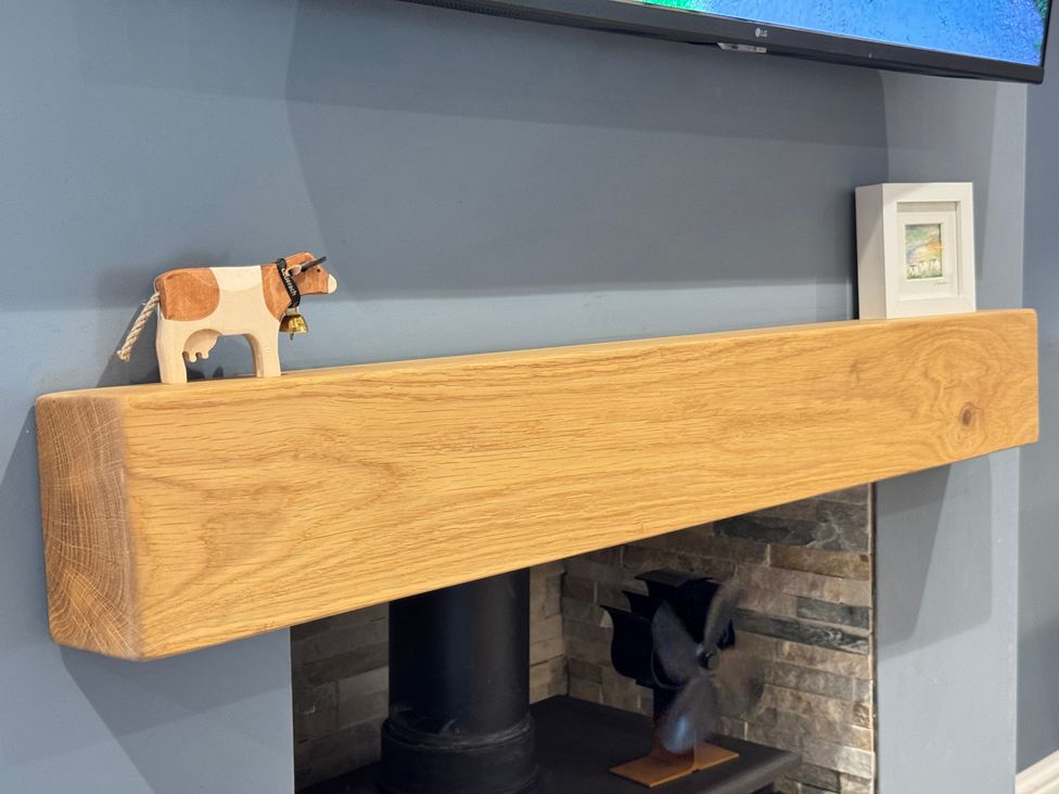A mantel with a cow figurine and picture frame at Railway Cottage in Penybontfawr
