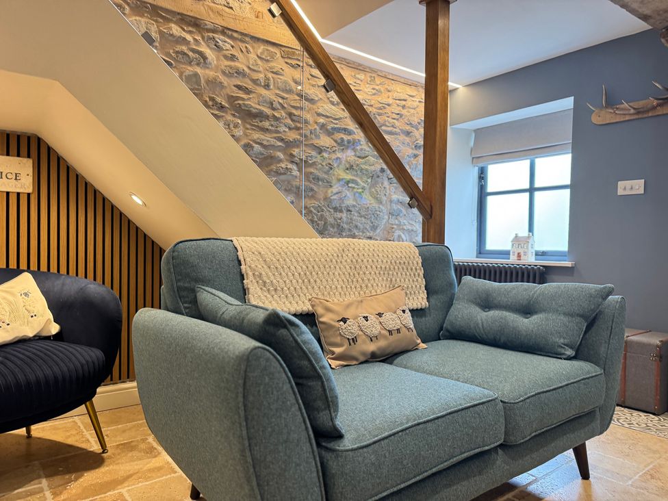 A living room with a sofa and armchair at Railway Cottage in Penybontfawr