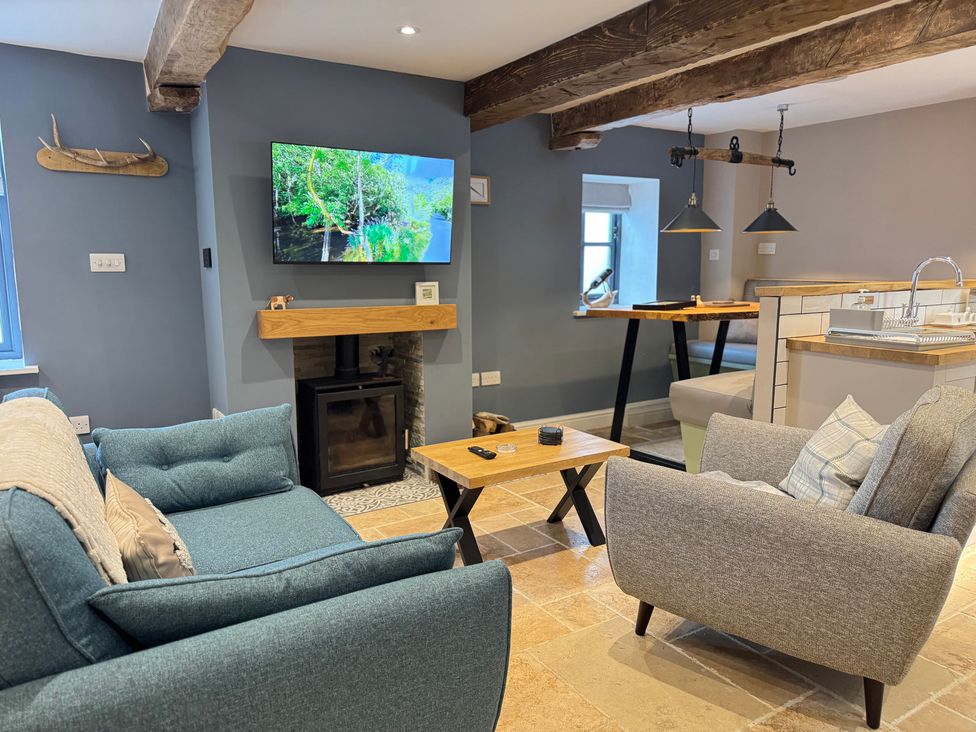 A living room with a sofa, armchair, coffee table, and television at Railway Cottage in Penybontfawr