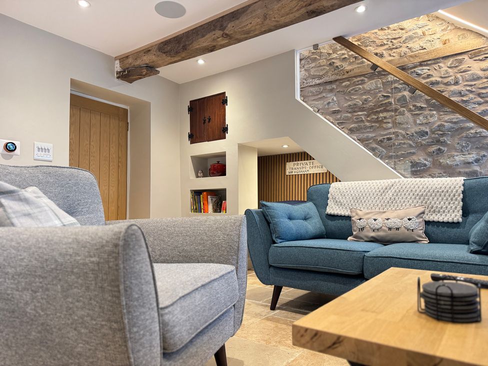 A living room with a sofa, armchair, and coffee table at Railway Cottage in Penybontfawr