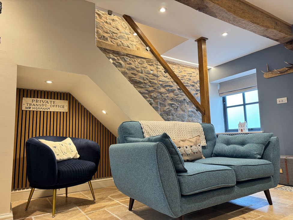 A living room with a sofa and armchair at Railway Cottage in Penybontfawr