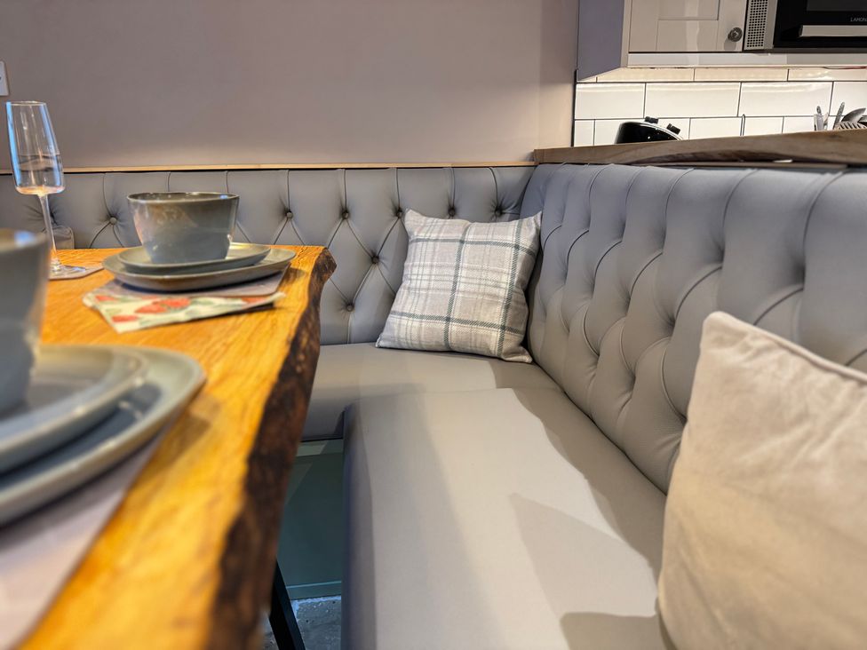 A dining area with a bench and tableware at Railway Cottage Penybontfawr