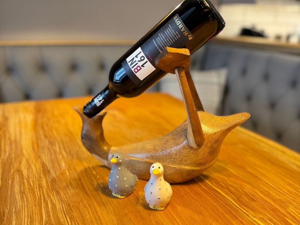 A wooden bird wine holder with a wine bottle and ceramic birds at Railway Cottage Penybontfawr