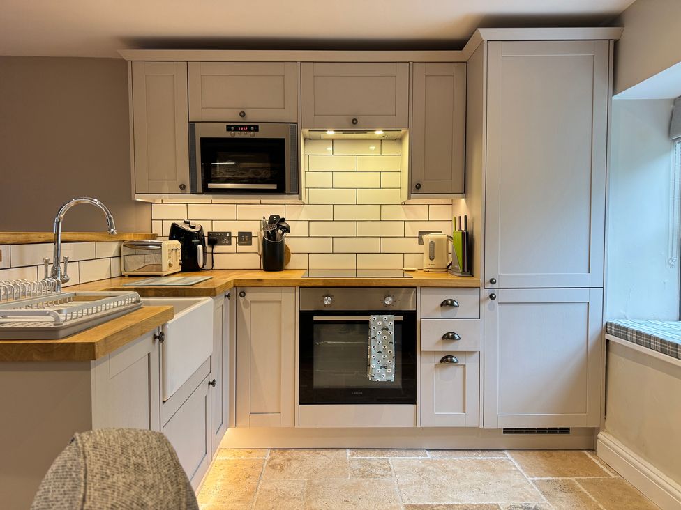 A kitchen with appliances and cabinets at Railway Cottage Penybontfawr