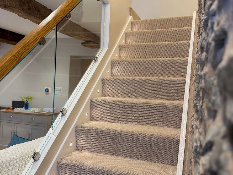 A staircase with carpet and glass railing at Railway Cottage in Penybontfawr