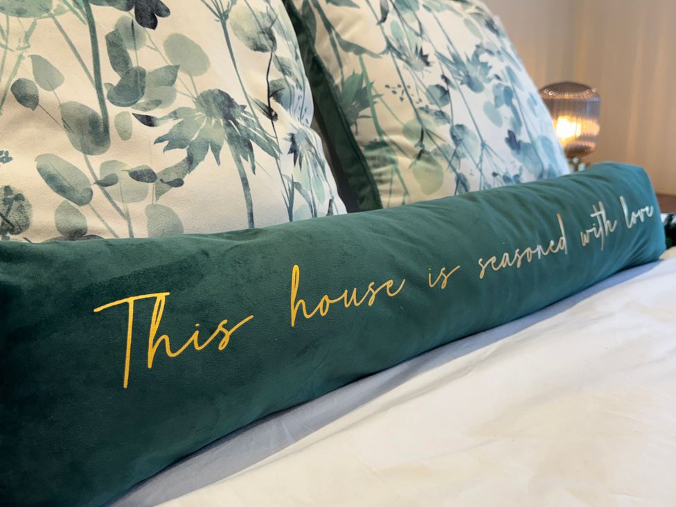 A decorative pillow with text on a bed at Railway Cottage in Penybontfawr