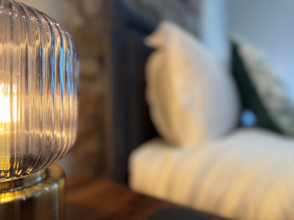 A bedside lamp and pillows in a bedroom at Railway Cottage in Penybontfawr