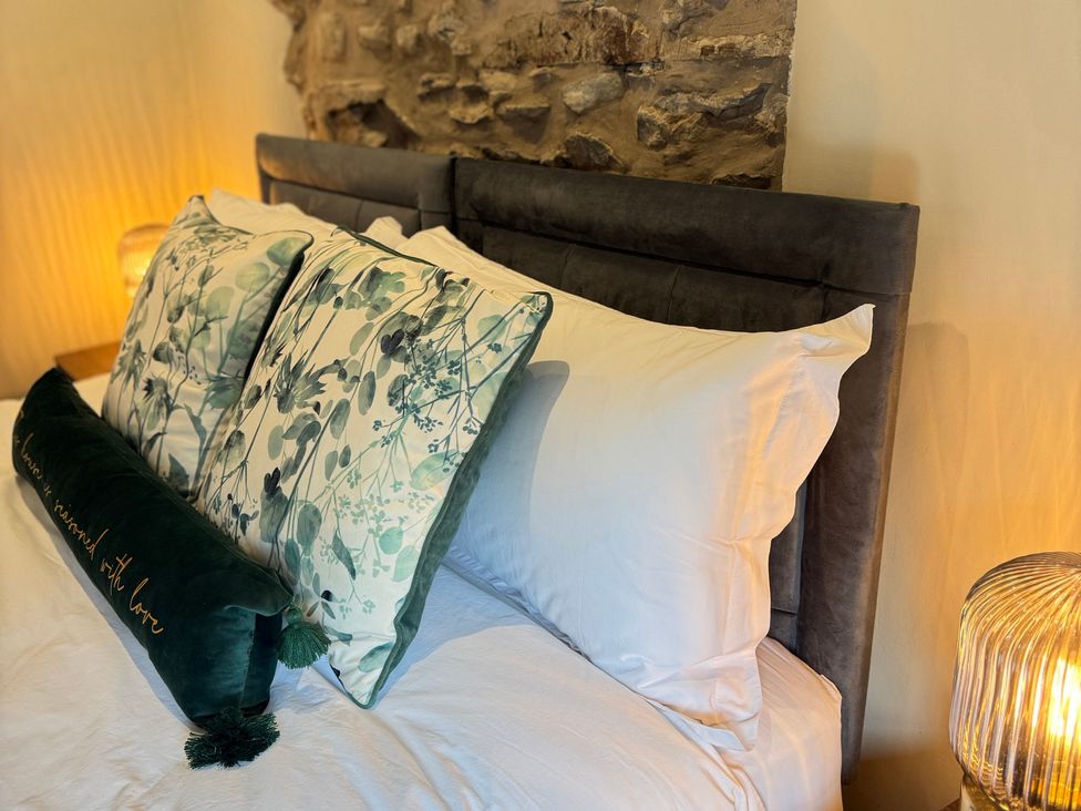 A bedroom with a bed and decorative pillows at Railway Cottage in Penybontfawr