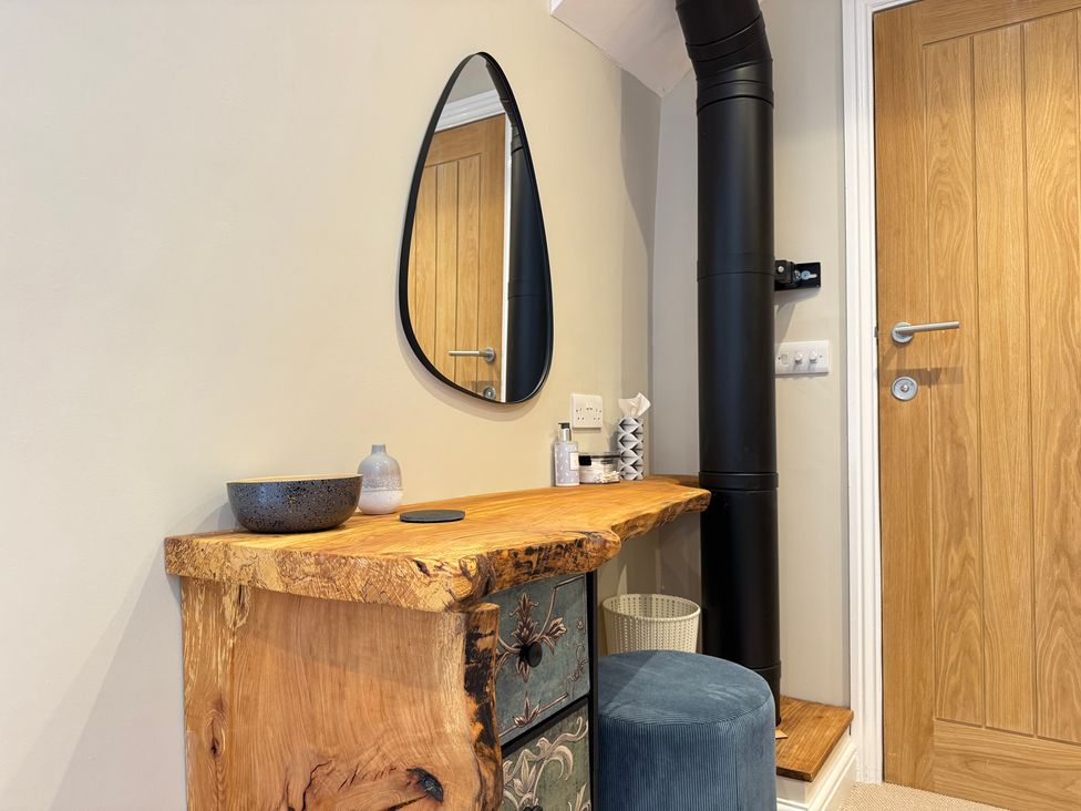 An entryway with a wooden table and mirror at Railway Cottage in Penybontfawr