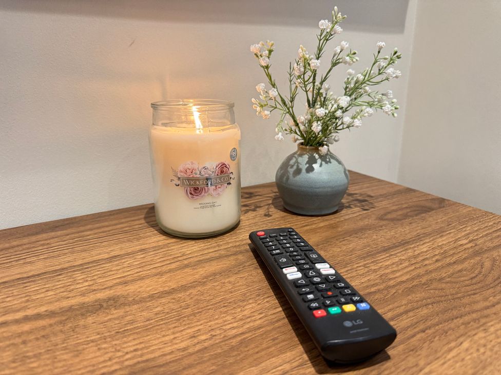 A table with a candle and remote control at Railway Cottage in Penybontfawr