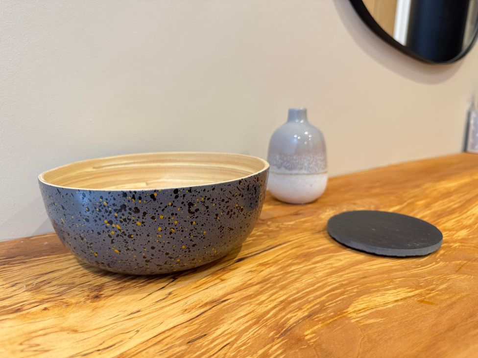 A bowl and a vase on a wooden table at Railway Cottage in Penybontfawr