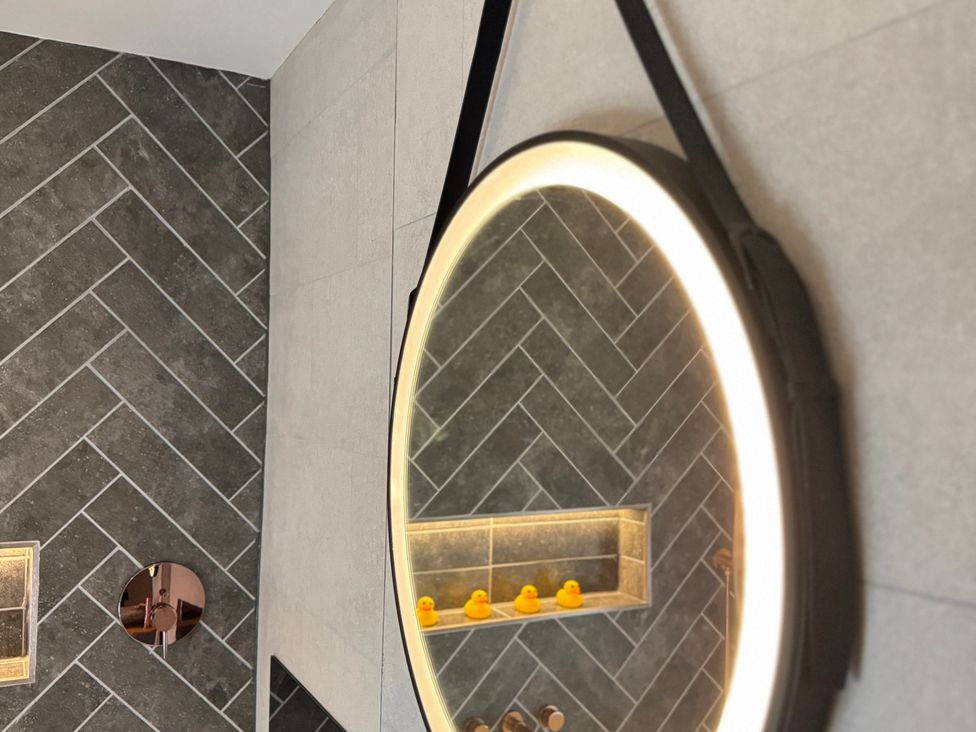 A bathroom with a mirror and rubber ducks on a shelf at Railway Cottage Penybontfawr